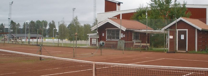 Tennisracket och boll på röd grusbana